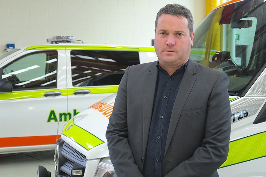 Robbie Moore standing in front of ambulances.