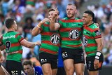 A South Sydney NRL player points his finger in celebration as he stands next to teammates after a try.