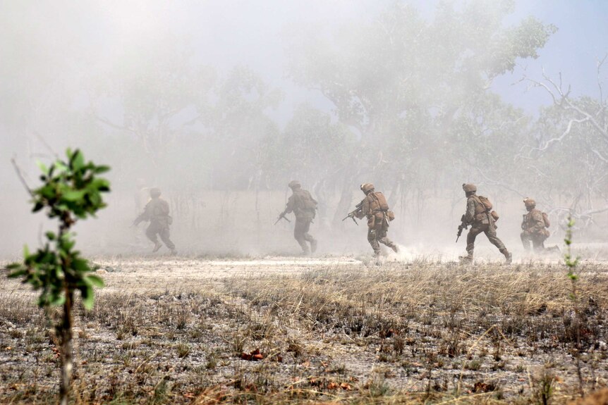 US marines run through smoke and dust