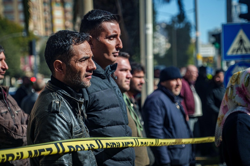 Men waiting behind Turkish police tape