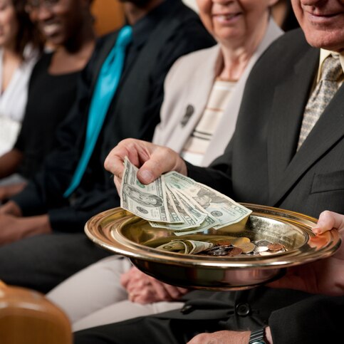 A collection plate with money in it is shown being passed.