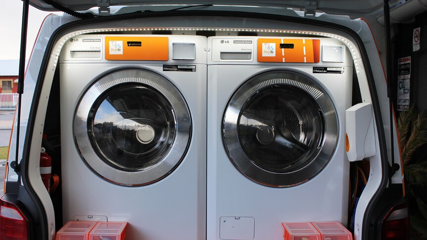 Two washing machines in the back of a Orange Sky Laundry van.