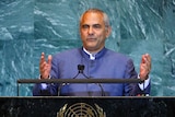 Jose Ramos-Horta wears a blue suit and speaks in front of a green marble wall at the UN