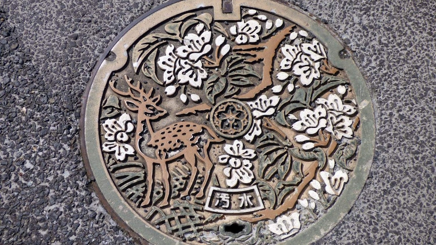 Manhole cover at Todaiji Temple in Nara, Japan shows a deer among a forest of cherry blossom.