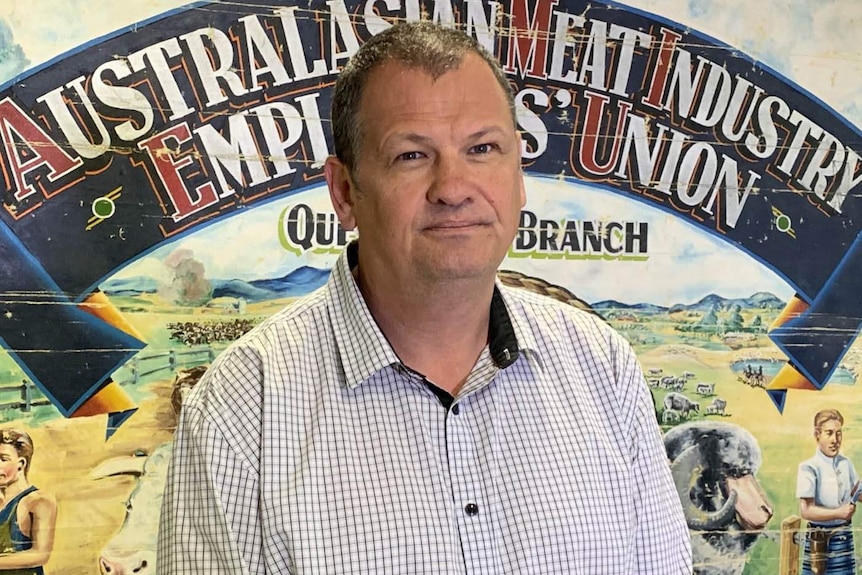 A man standing in front of a banner for the meat industry employees union.