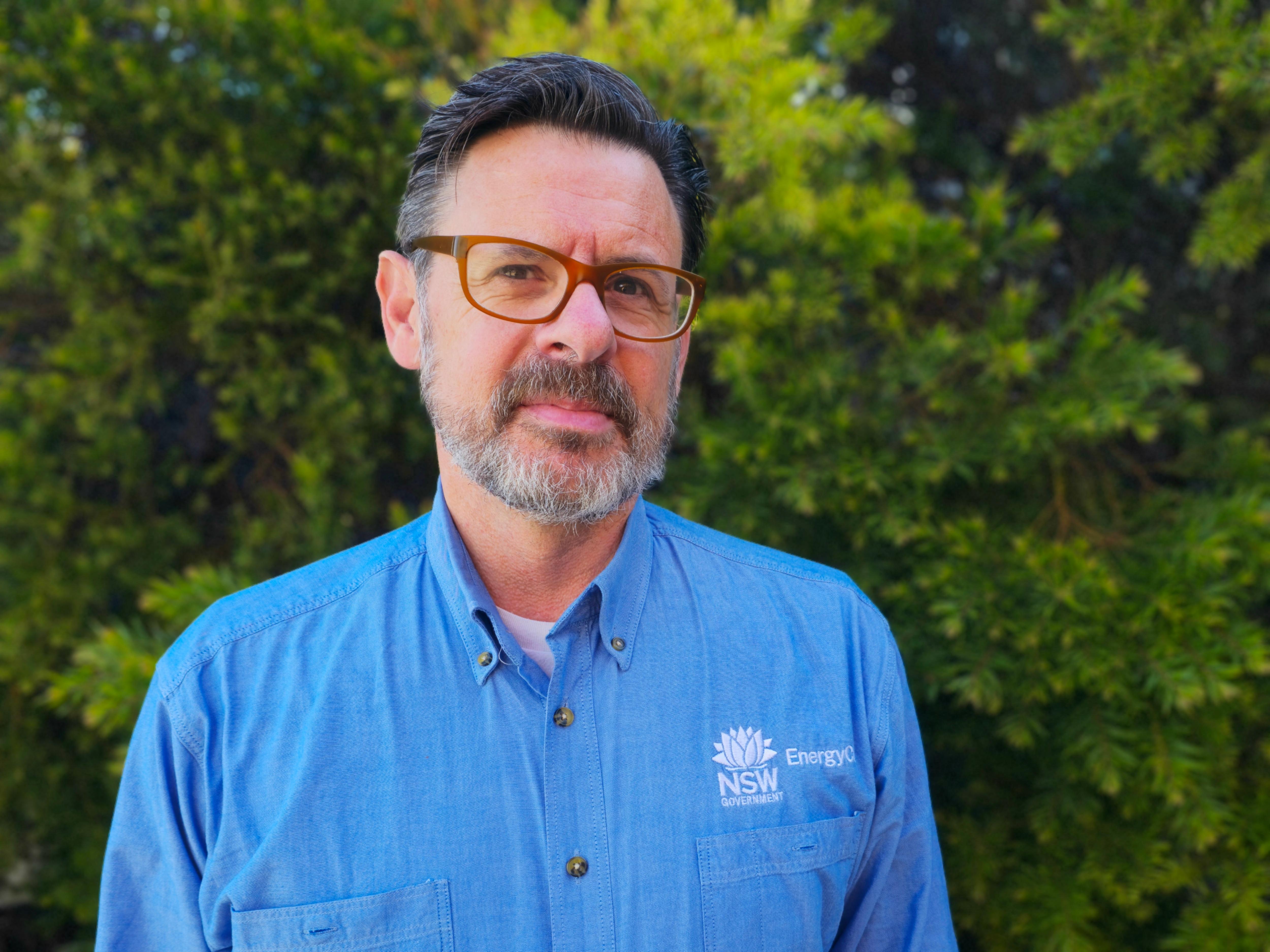 A man in glasses and a bright blue shirt labelled EnergyCo