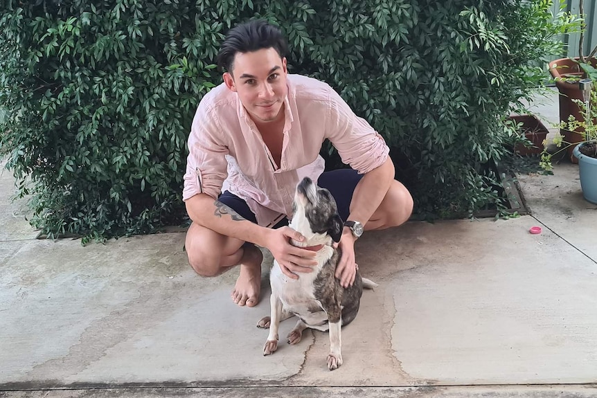 A young man, University of Queensland student Jaidyn Snowden, poses with his dog