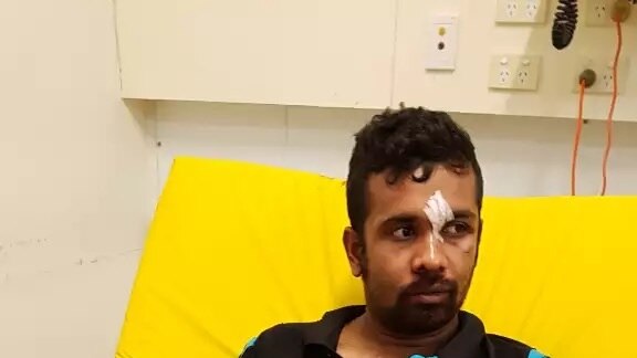 Kamal Parvez at a hospital in Nauru after receiving treatment. There is blood on his hands and bandages between his eyes.