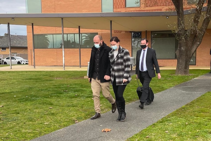 man and woman wearing mask holding hands walking