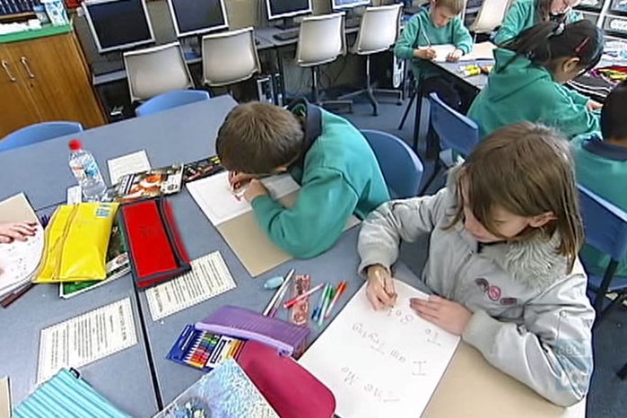 Primary school students working at a desk in a classroom in Canberra.