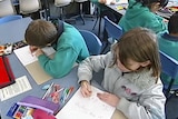 Children work at classroom desks.