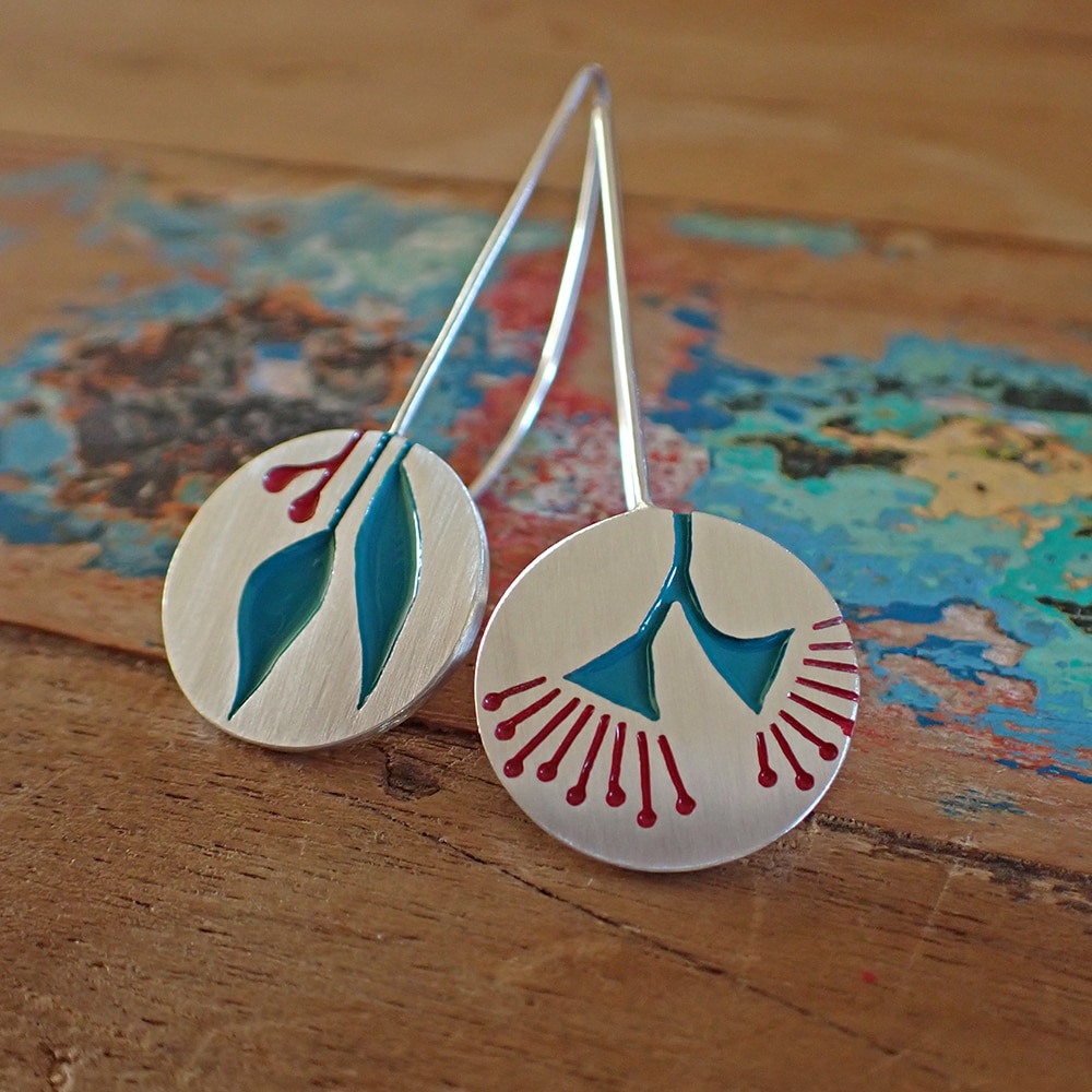 A pair of drop earrings with floral designs on them