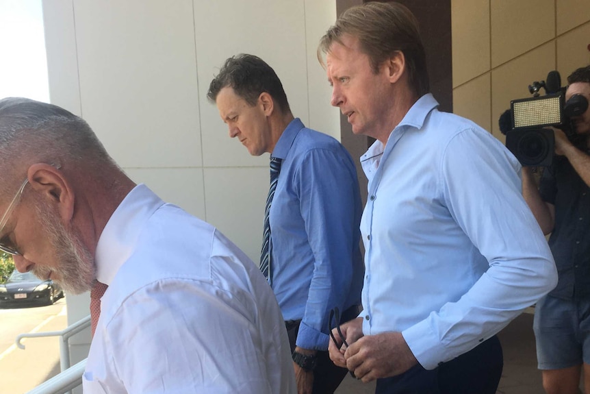 Three men in business shirts walk down the steps outside a court.