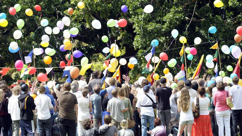 A group of mourners at a funeral release a bunch of balloons