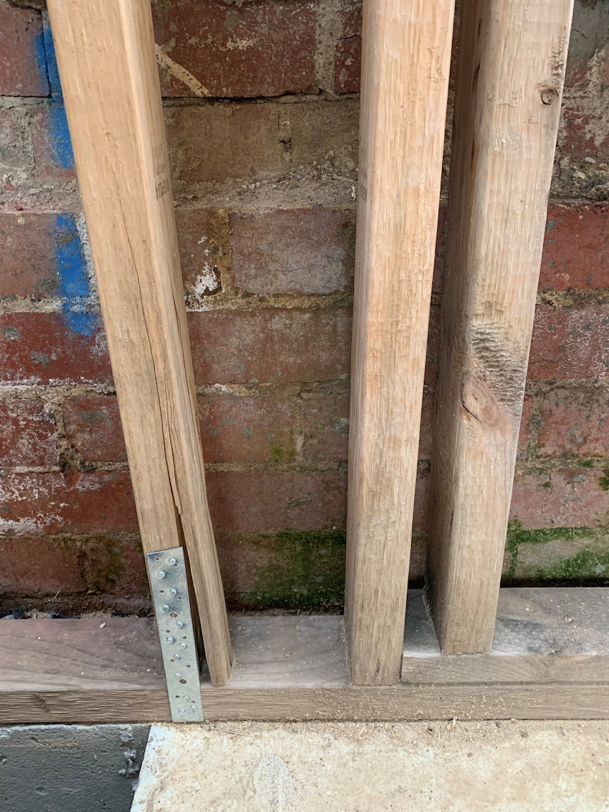 A split and gap runs down the verticle wooden post of the house frame.