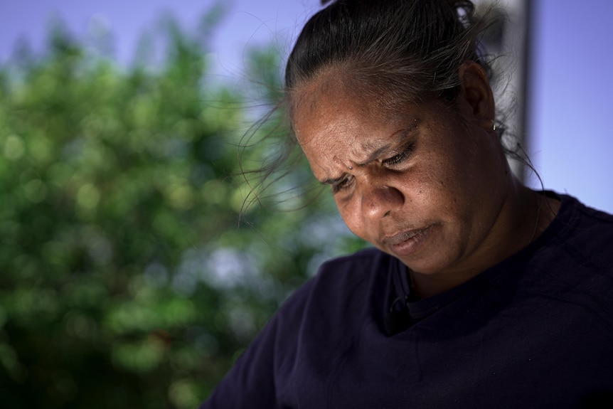 an aboriginal woman looking down with a furrowed brow