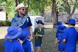 A group of school kids gather around their principal on the school oval.