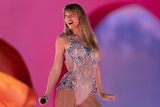 Taylor Swift smiles as she performs on stage.