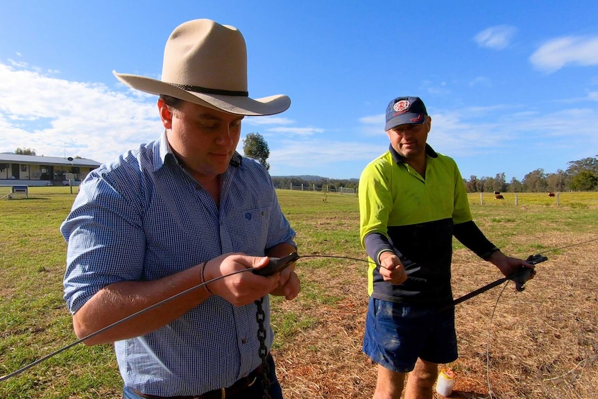 Farmers Josh and Andy Gilbert tending to a fence on their property for an article about farmers and climate change.