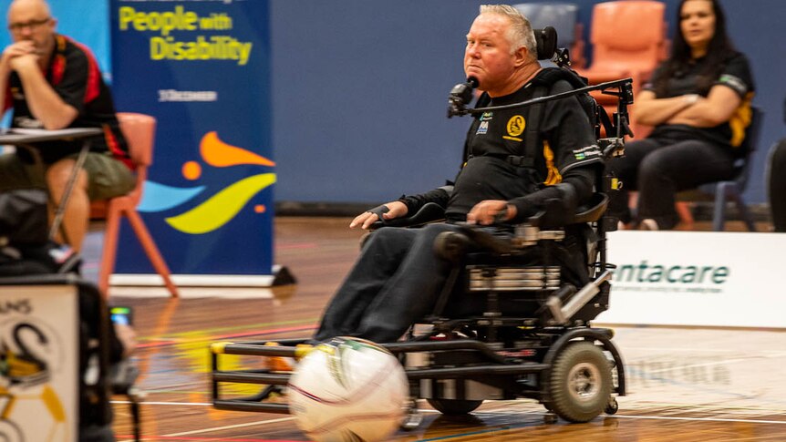 A man in a wheelchair watches the ball while controlling the chair with his chin