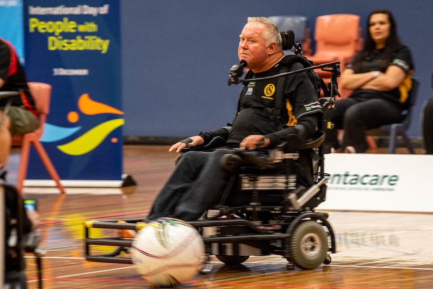 A man in a wheelchair watches the ball while controlling the chair with his chin