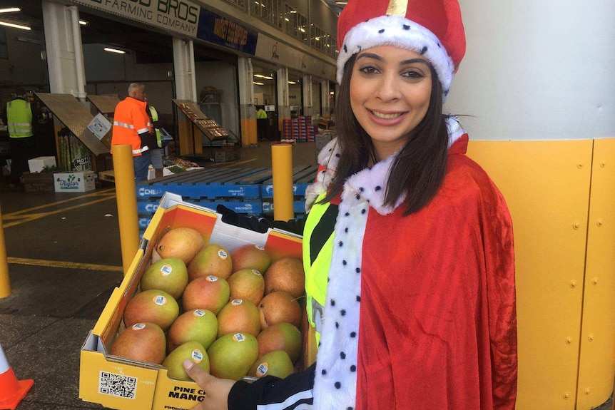 A woman holding a tray of mangoes.