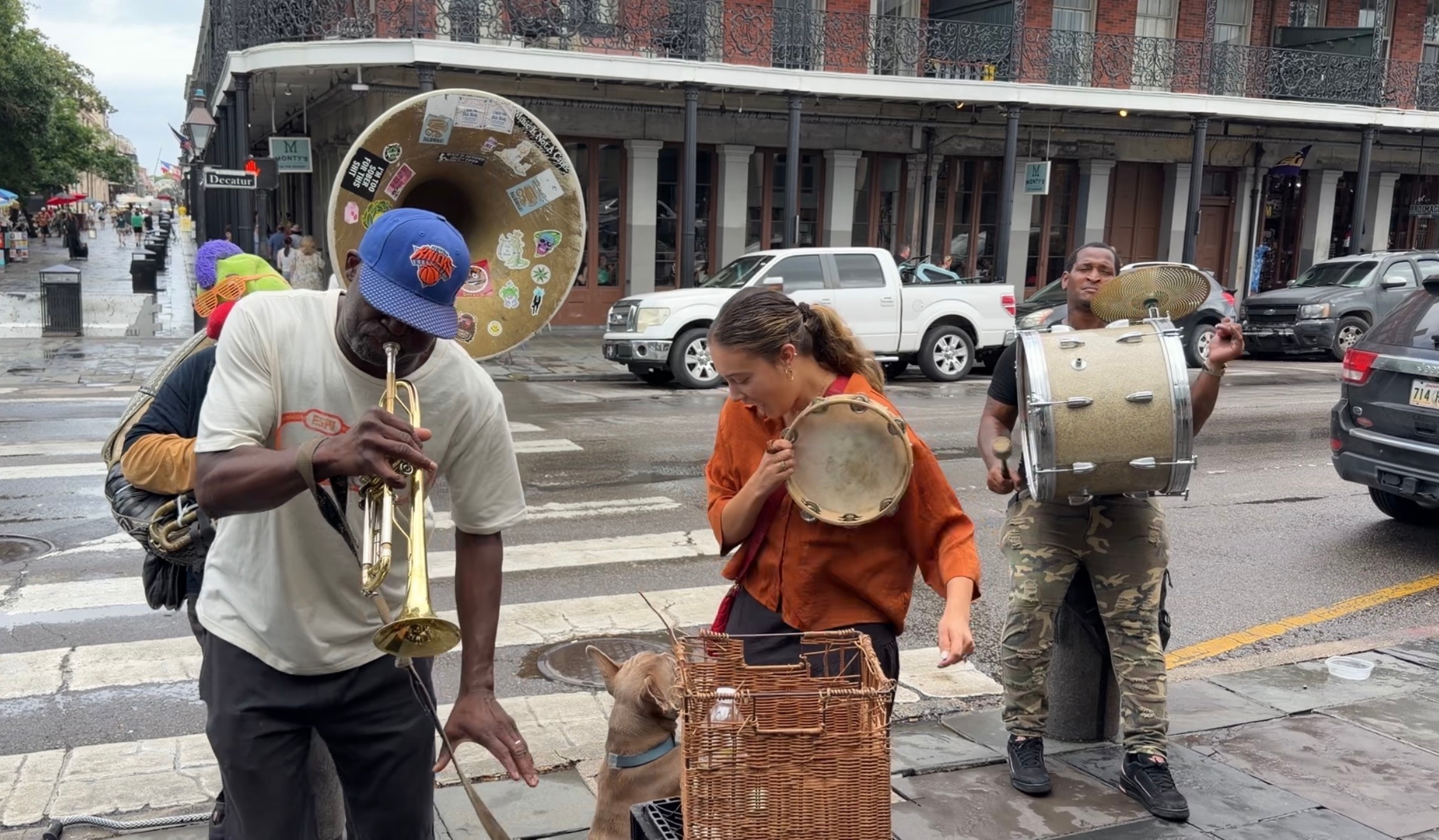 Mikaela sostiene una pandereta en la calle mientras otros artistas tocan instrumentos.