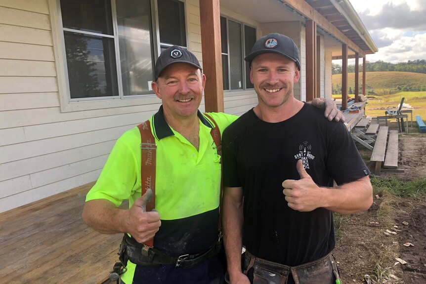 Two builders standing in front of house with thumbs up