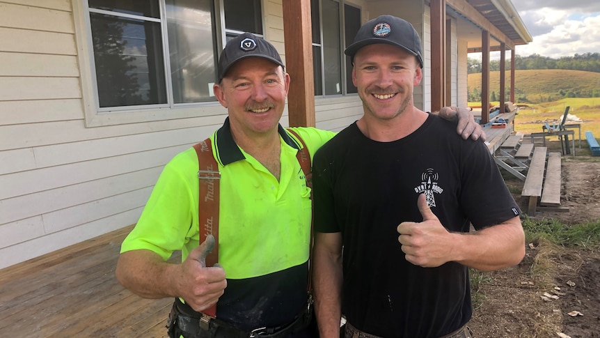 Two builders standing in front of house with thumbs up