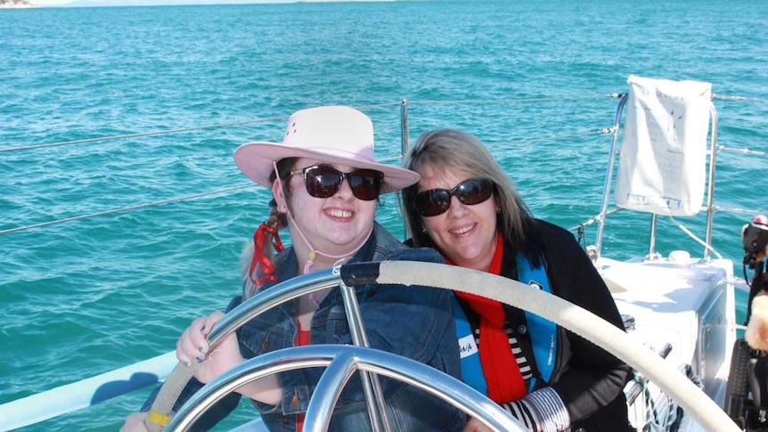 Mother and daughter smiling and steering the yacht.