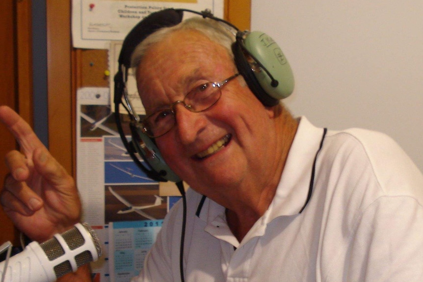A man with headphones on talking on a microphone.