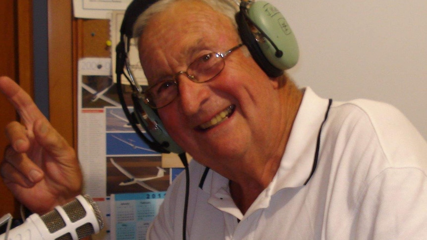 A man with headphones on talking on a microphone.