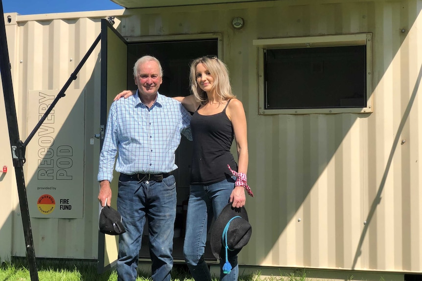 An elderly man and a woman standing in front of a recovery pod