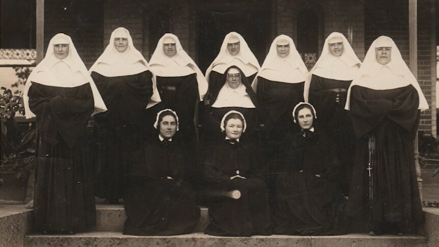 Postulants and novices lined up on a step in front of a door.