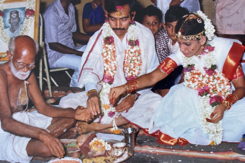 A couple seated during a traditional Indian wedding ceremony, surrounded by floral offerings