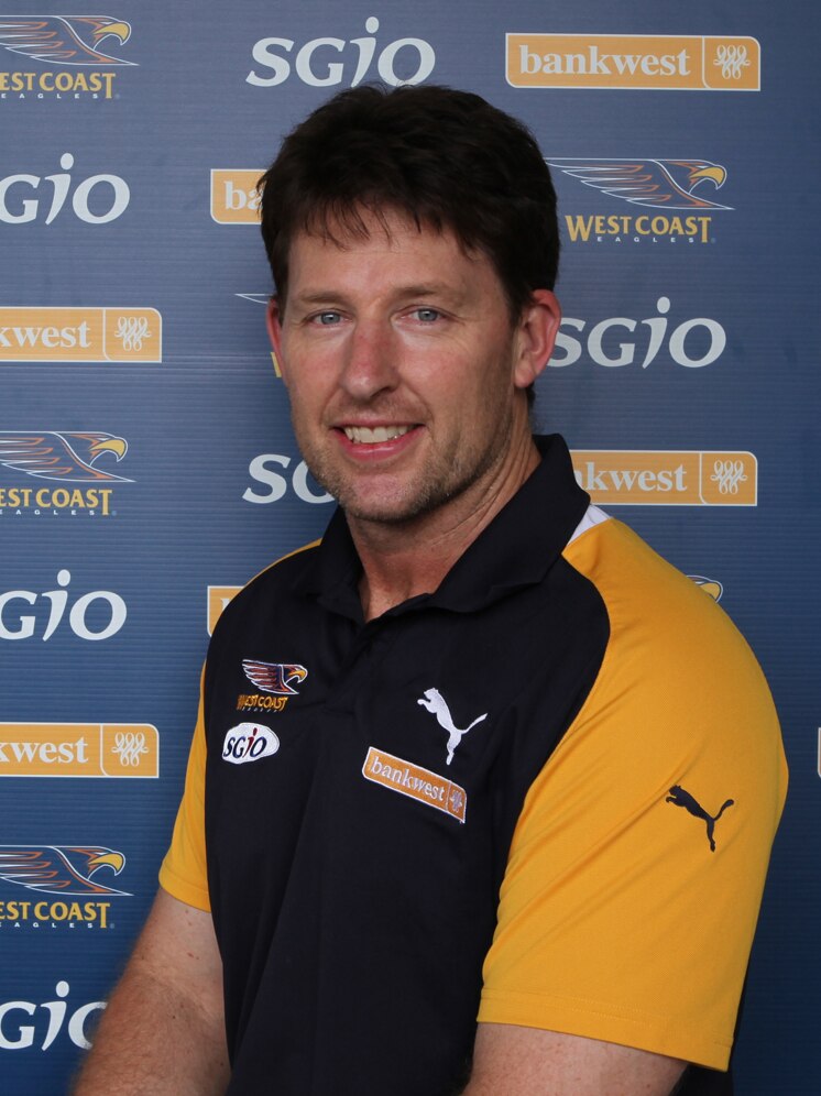 Man in sports clothing in front of a West Coast Eagles pull up banner