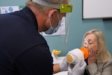 A woman blows into a mouthpiece during a health study.