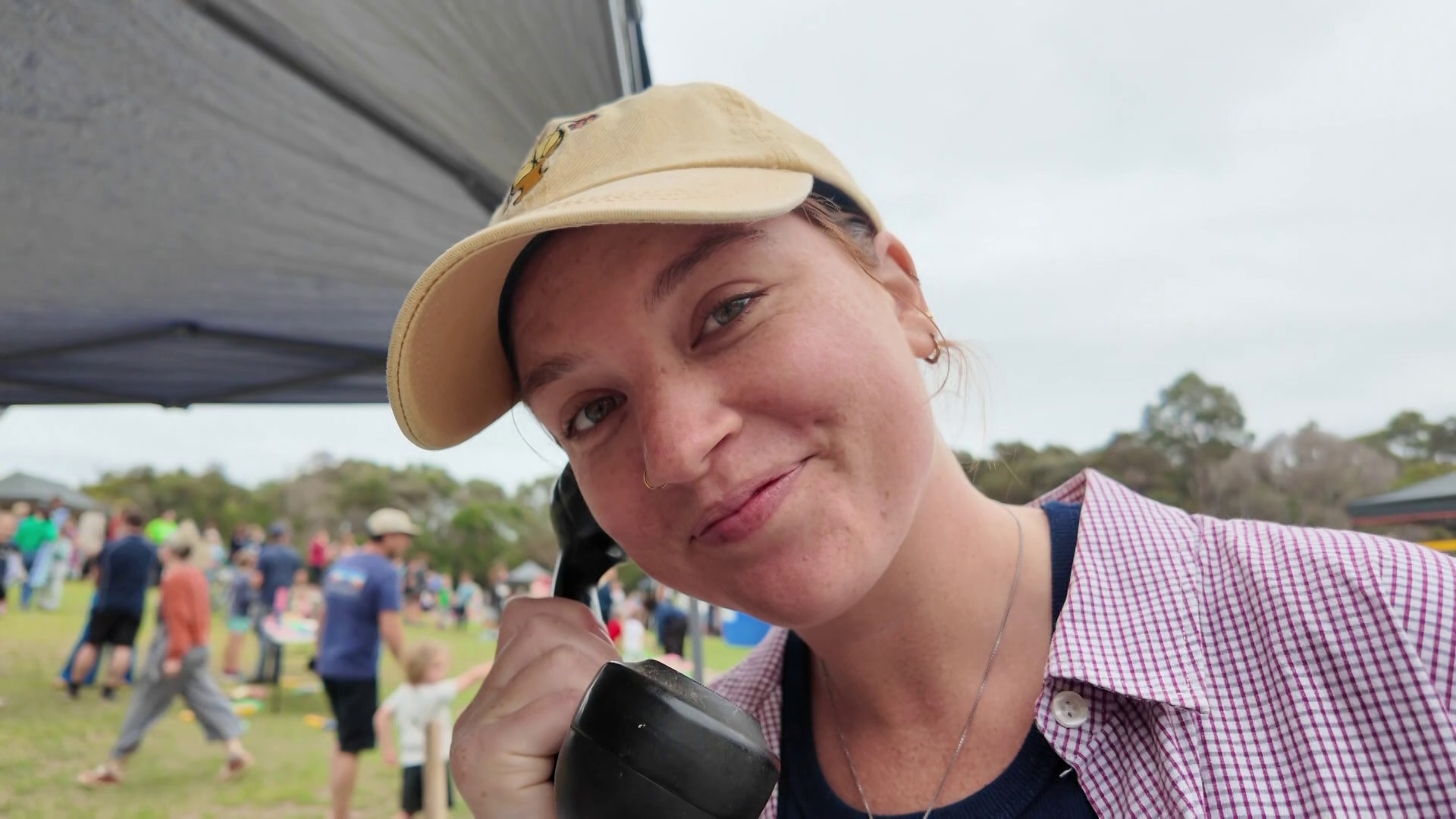 Una mujer joven sostiene un viejo auricular de teléfono en su oreja