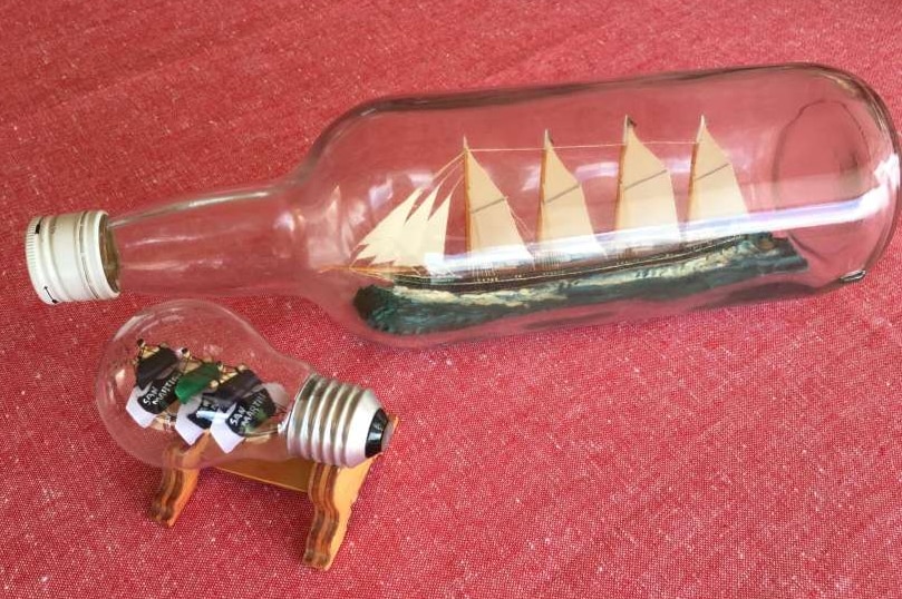 Two ships in bottles are on display, including one in a lightbulb.