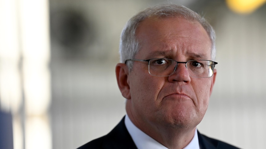Scott Morrison wears a suit and frowns while looking at the camera. 