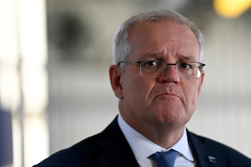 Scott Morrison wears a suit and frowns while looking at the camera. 