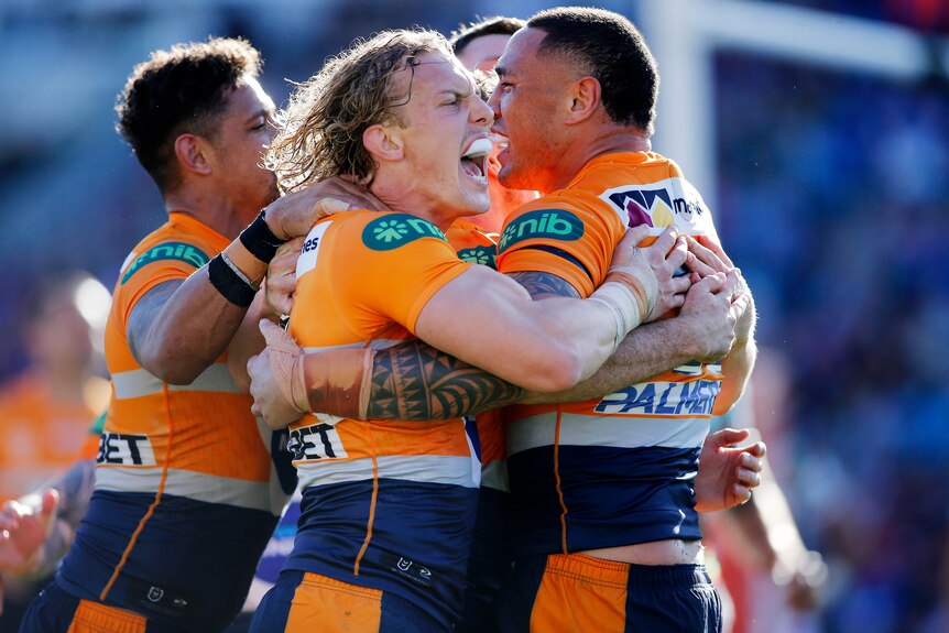 Newcastle Knights NRL players embrace as they celebrate scoring a try against South Sydney Rabbitohs.