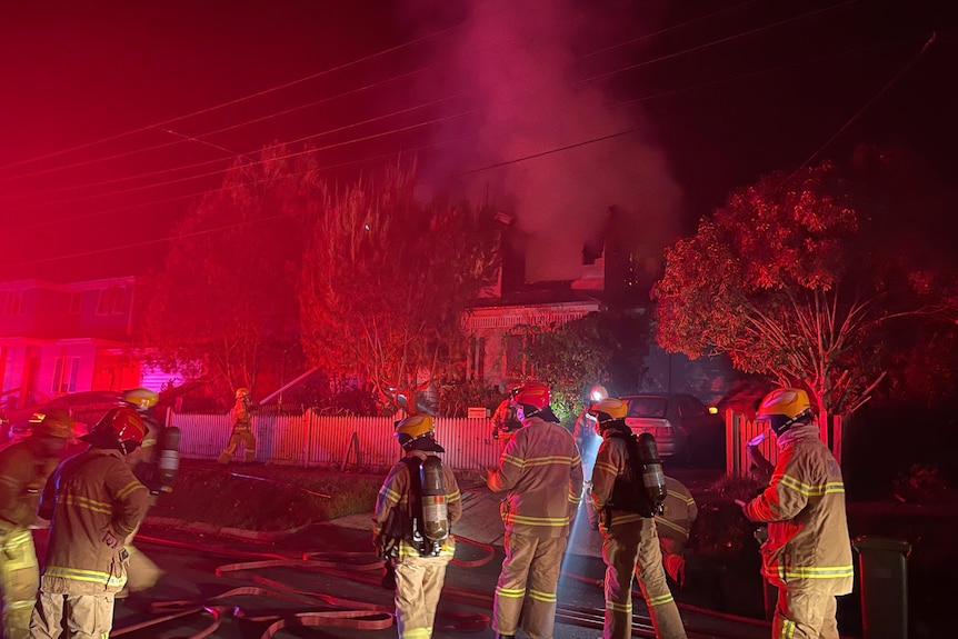 Fire brigade officers attend to a house fire