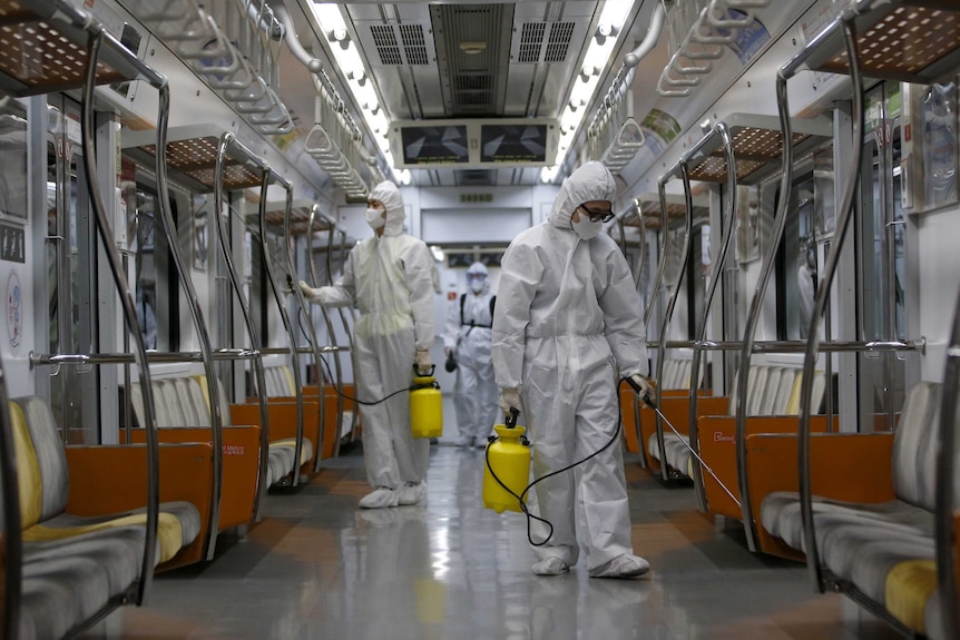 Workers in full protective gear disinfect the interior of a subway train in Seoul