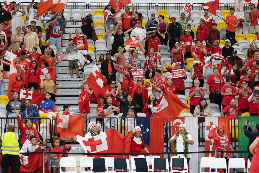 A wide shot of Tongan fans, banners, flags and celebration 