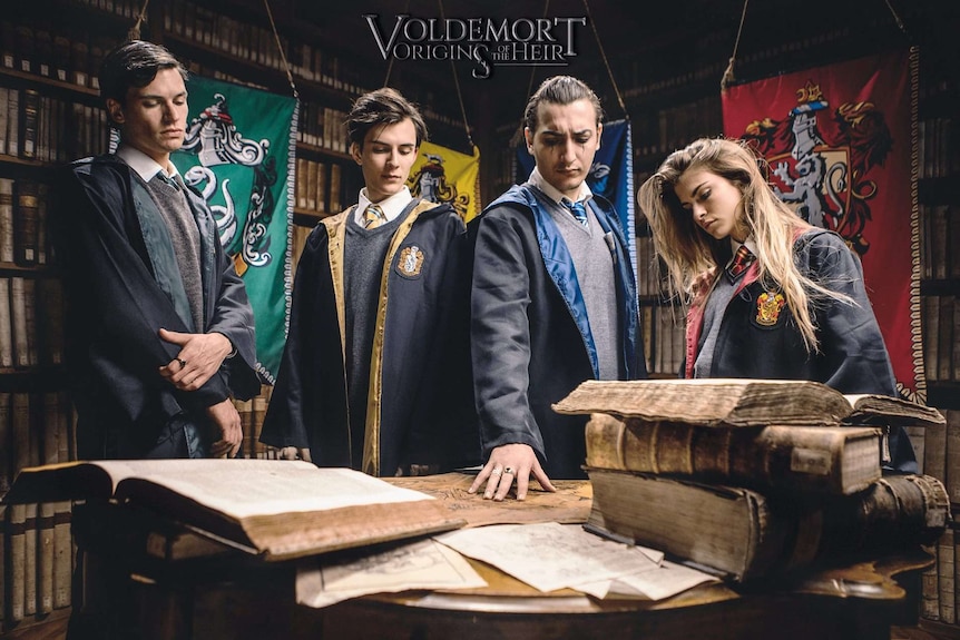 The heirs of the Hogwarts houses look at books on a table.