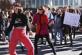 Dancers, some with signs stand in Garema Place, some wearing sunglasses.