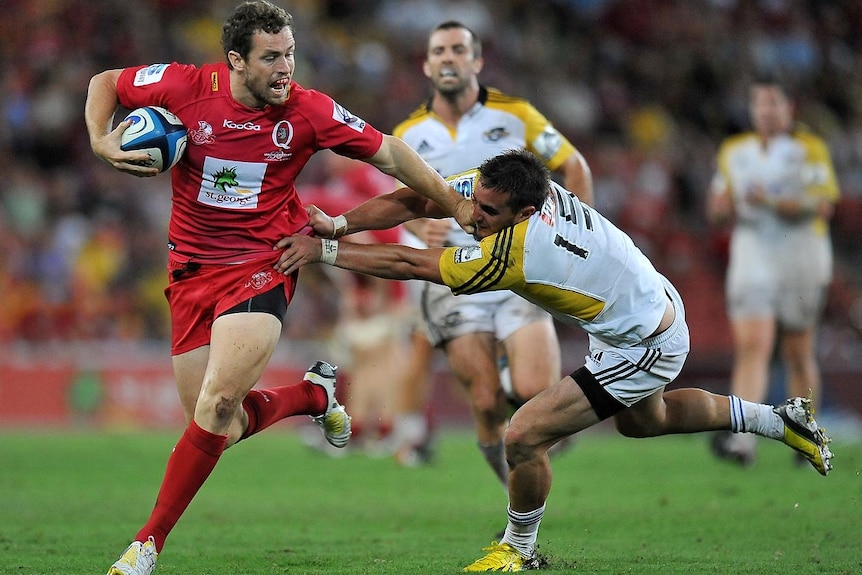 Luke Morahan fends off a Hurricanes player.