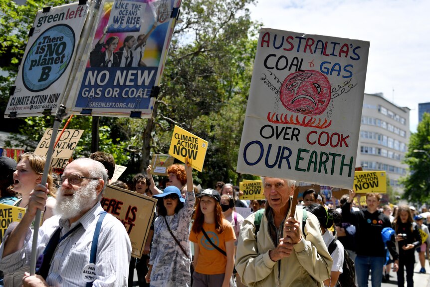 Los manifestantes sostienen pancartas exigiendo medidas sobre el cambio climático mientras caminan por una calle importante.