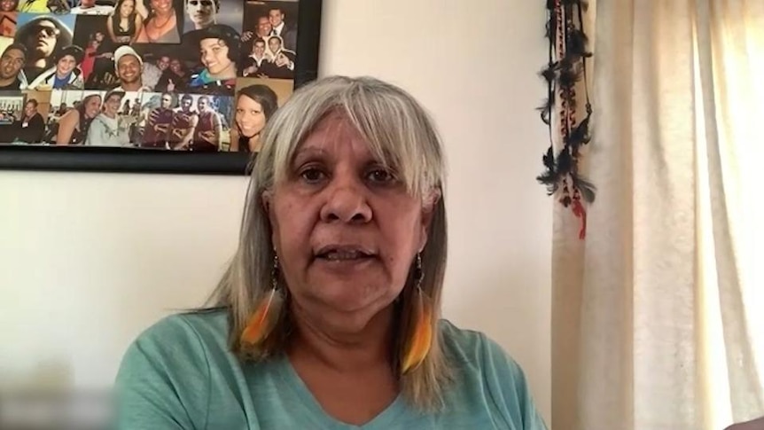 Indigenous woman sits near photo board